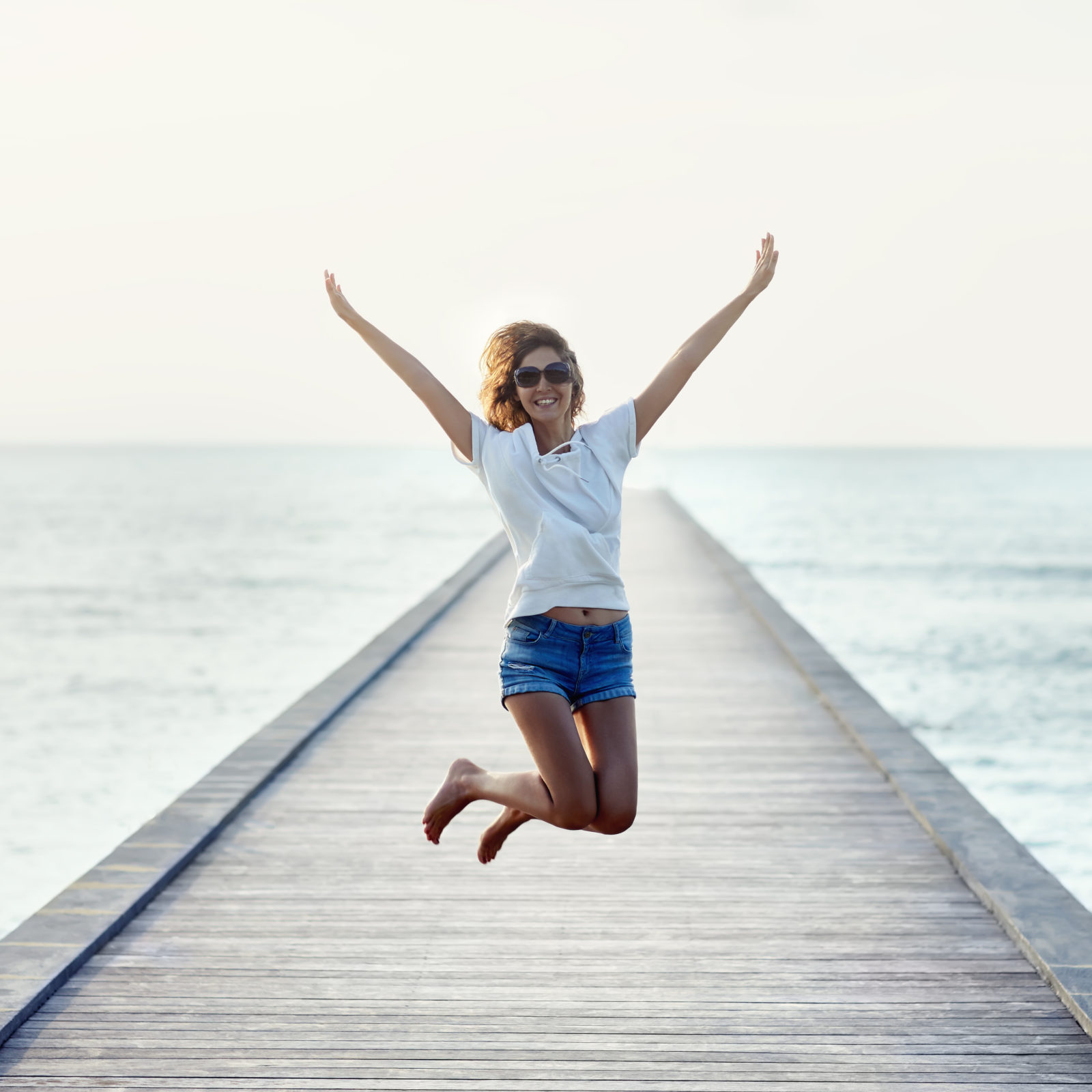 Happy jumping girl on the pier. Freedom concept